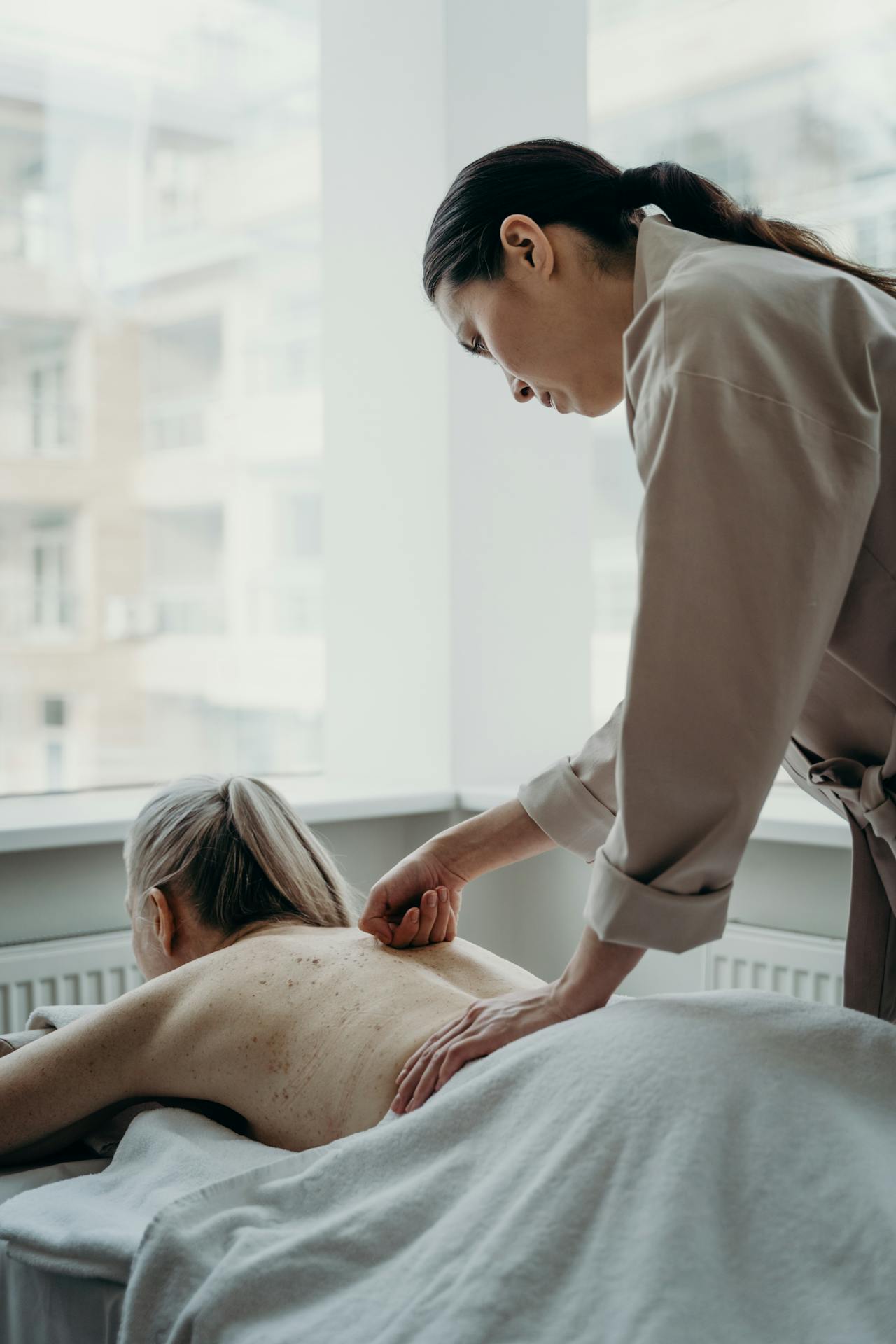 NCBTMB-certified massage therapist placing heated basalt stones along a client's back during a hot stone massage